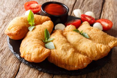 Kızarmış panzerotti domates, otlar ve mozzarella yakın çekim bir kara tahta üzerinde bir dolgulu. Horizonta
