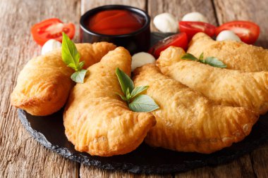 Baharatlı tipik sokak Italyan Mutfagi: domates sos, otlar ve mozzarella yakın çekim bir kara tahta üzerinde ile kızarmış panzerotti. Horizonta