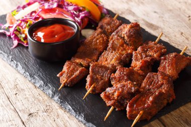 Recipe of a spicy African suya kebab on skewers with fresh vegetable salad and ketchup close-up on a table. horizonta clipart