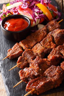 Suya - kızartma Afrika baharatlı saptırılmış sığır eti kebabı taze sebze salatası ve ketçap yakın çekim tablo ile servis edilir. dikey