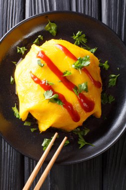 ahşap bir masa üzerinde siyah bir plaka üzerinde pirinç, tavuk, sebze ve domates soslu Japon omlet tarifi. Abov gelen dikey üstten görünüm