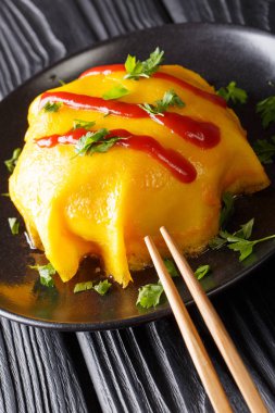 Pirinç, tavuk ve sebze doldurulmuş lezzetli omurice omlet masada bir tabakta servis. Vertica