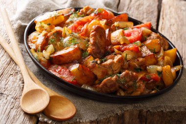 Gürcü akşam yemeği: kızarmış patates, domates, soğan, otlar ve baharatlar yakın çekim bir tabloda bir tava etli. Horizonta