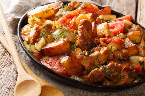 Ojahuri etli patates, domates, otlar ve baharatlar yakın çekim bir tavada bir tablo üzerinde kızarmış. Horizonta