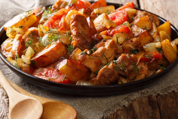 Fried meat with potatoes, tomatoes, herbs and spices close-up on — Stock Photo, Image