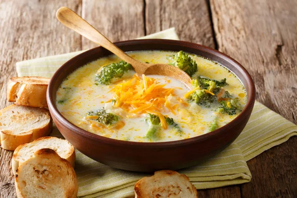 Traditional recipe of broccoli cheese soup with vegetables in a bowl with toast close-up on the table. horizonta