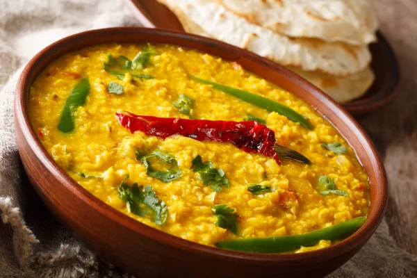 Punjabi recipe Dal Tadka vegetarian yellow lentils with spices served flat bread close up in a bowl on the table. horizonta