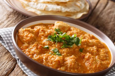 Yavaş zengin malzemeyi krema, kaju fıstığı, ghee ve masada bir tabakta seviyor yakın çekim ile komple pişirme tavuk changezi. Horizonta