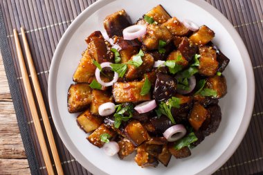 Chinese style eggplants in spicy soy sauce with ginger, garlic, pepper, closeup on a plate on the table. horizontal top view from abov clipart