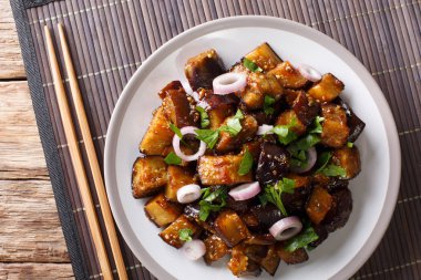 Chinese Yu Xiang Eggplant fried in soy sauce with ginger, garlic, pepper, closeup on a plate on the table. horizontal top view from abov clipart