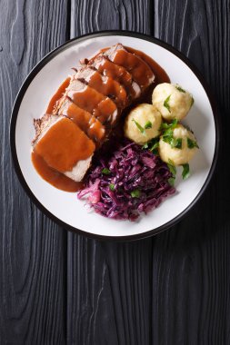 Festive German full dinner Sauerbraten - beef stew with gravy served with potato dumplings and red cabbage close-up on a plate. Vertical top view from abov clipart
