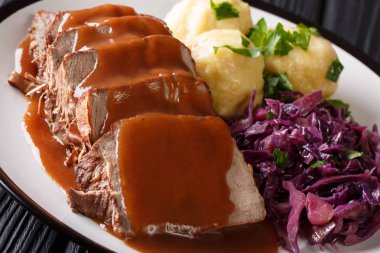 Festive German full dinner Sauerbraten - beef stew with gravy served with potato dumplings and red cabbage close-up on a plate. Horizonta clipart