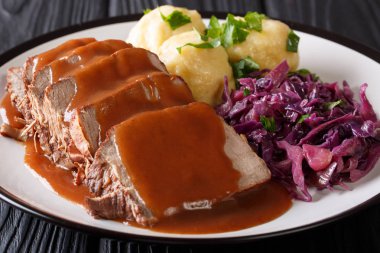 Slow Cooker Pot Roast Sauerbraten with spicy sauce, potato dumplings and red cabbage close-up on a plate. horizonta clipart