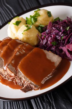 German national dish Sauerbraten served with knodel potato dumplings and red cabbage close-up on a plate. vertica clipart