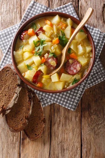 Vegetable thick potato soup with sausages in a bowl close-up. Ve