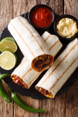 Lezzetli kızarmış börek ve soslar yakın çekim masanın üzerine kıyma, fasulye, Mısır, biber ve domates ile doldurulmuş. Yukarıdan, rustik styl dikey üstten görünüm