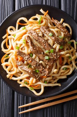 Sığır eti teriyaki udon erişte, havuç ve yeşil soğan yakın masada bir plaka üzerinde çekim kısmı. Abov gelen dikey üstten görünüm
