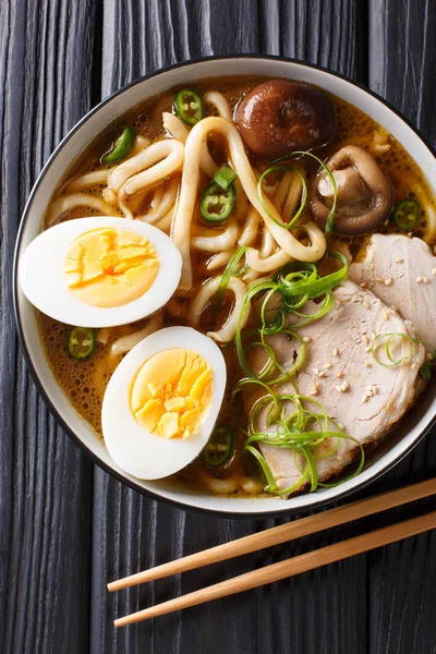 Traditional Japanese udon noodle soup with pork, boiled eggs, mu