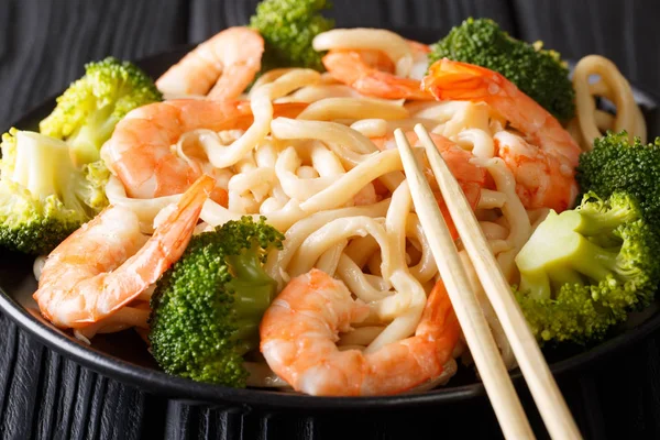 Udon-Nudeln mit Shrimps und Brokkoli in Nahaufnahme auf einem Teller. horiz — Stockfoto