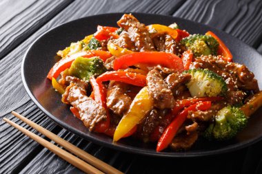 Kırmızı ve sarı biber ile baharatlı teriyaki sığır, masaya bir tabak brokoli ve susam tohumu yakın çekim. Asya tarzı. Horizonta