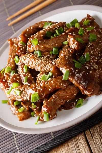 masanın üzerinde bir plaka üzerinde yeşil soğan ve susam yakın çekim ile teriyaki sığır eti. Vertica
