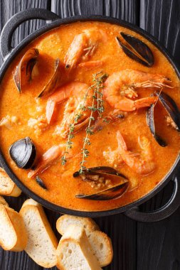 Masanın üzerinde bir tavada deniz ürünleri, patates, otlar ve balık yakın çekim ile İspanyol Suquet de Peix çorbası. Abov gelen dikey üstten görünüm