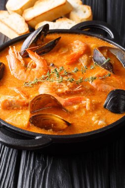 Deniz ürünleri Suquet de Peix çorbası patates, otlar ve balık picada yakın çekim masanın üzerinde bir tencerede ilavesi ile. Vertica