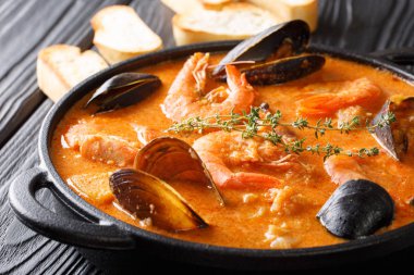 Masanın üzerinde bir tencerede picada yakın çekim ilavesi ile zengin deniz ürünleri Suquet de Peix patates, otlar ve balık çorbası tadı. Horizonta