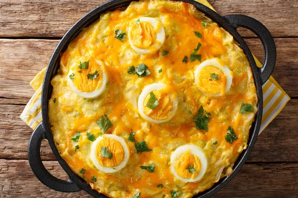 Authentic British food. Anglesey eggs baked with mashed potatoes, leek cheese sauce close-up on the table. horizontal top view from abov