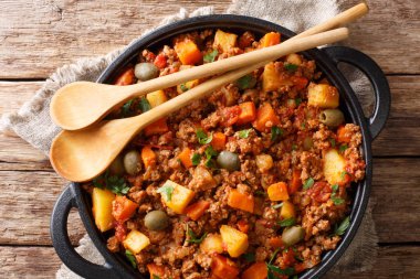 Bir Pan masanın üzerine domates sosu closeup picadillo tarifi kıyma, havuç ve patates pişmiş. Dikey