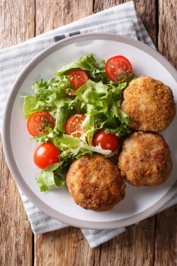 Karbonaderbreaded domuz eti Pattyrecipe ile masaya bir tabak taze sebze salatası yakın çekim. Yukarıdan dikey üstten görünüm