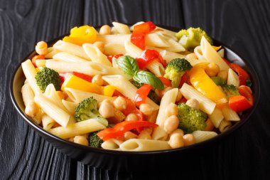 Vejetaryen menü penne makarna ile nohut, sebzeler, otlar ve baharatlar closeup masaya bir tabak içinde. Horizonta