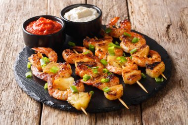 Kebap ızgara deniz ürünleri karides ve ananas dilimleri ile ahşap bir masa kayrak bir tabağa soslar yakın çekim üzerinden. Horizonta