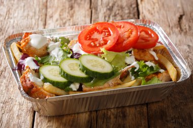 Patates kızartması, tavuk, taze salata, peynir ve sos içinde bir yakın çekim folyo tepsi masanın üzerine gelen paket servisi olan restoran Hollandalı kapsalon. Yatay