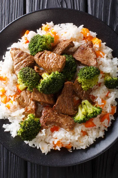 Roasted beef with broccoli with rice and persimmon side dish close-up on a plate on the table. horizontal