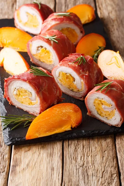 Pork tenderloin baked in prosciutto and stuffed with persimmon and cheese close-up on the table. vertica