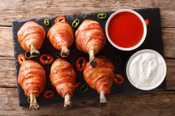 Bacon Wrapped Chicken Lollipops with sauces close-up on the table. horizontal top view from abov