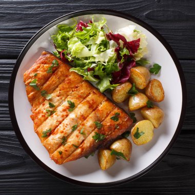 Izgara biftek kılıçbalığı bebek patates ve taze salata yakın çekim siyah bir zemin üzerine bir tabakta servis. abov üzerinden üstten görünüm