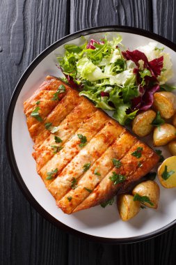 Patates kızartması ve taze salata yakın ahşap bir masa üzerinde bir plaka üzerinde çekim ile ızgara kılıç balığı fileto. Abov gelen dikey üstten görünüm