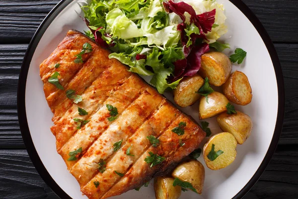 Fried swordfish biftek bebek patates ve ahşap bir masa üzerinde bir tabak taze salata yakın çekim. abov üzerinden yatay üstten görünüm