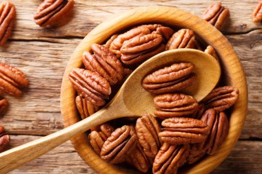 Bowl with pecan nuts on wooden table closeup. horizontal top view from abov