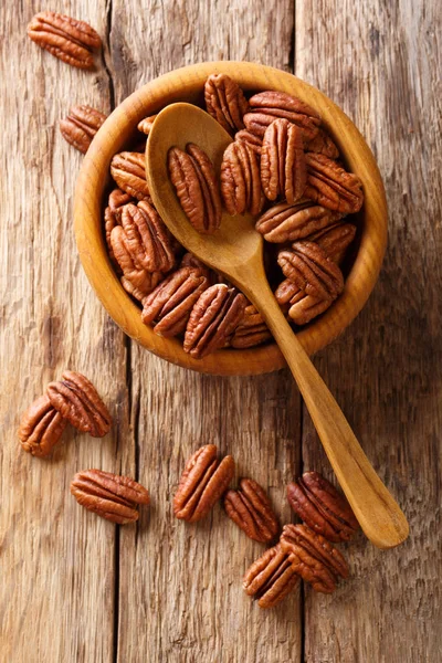 Pecans ahşap bir masa üzerinde bir kasede yarım. Yukarıdan, rustik styl dikey üstten görünüm