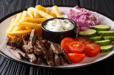 Sığır eti hünkar bir plaka ile patates kızartması, salata ve sos yakın çekim ahşap bir masa üzerinde. Horizonta