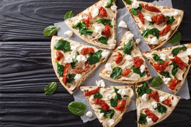 Düz ekmek Humus, kurutulmuş domates, ıspanak ve keçi peyniri yakın çekim masanın üzerinde. Abov üzerinden yatay üstten görünüm