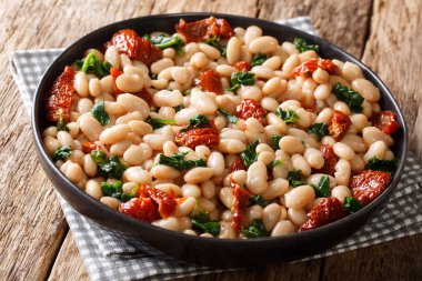 Acılı fasulye güveç ıspanak, sarımsak ve kurutulmuş domates closeup masada bir tabakta. Horizonta