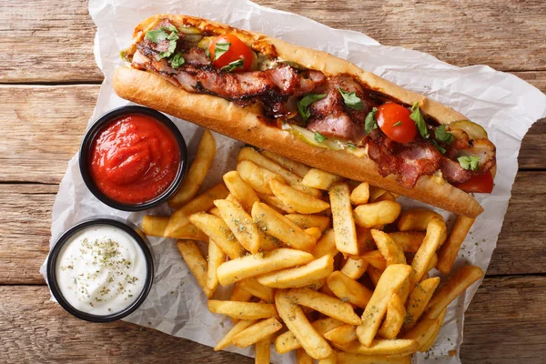 American hot dog with fried bacon, vegetables, french fries and — Stock Photo, Image