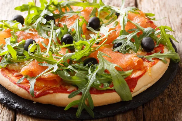 Łosoś Pizza ze świeżą arugula, czarne oliwki i ser zbliżenie — Zdjęcie stockowe