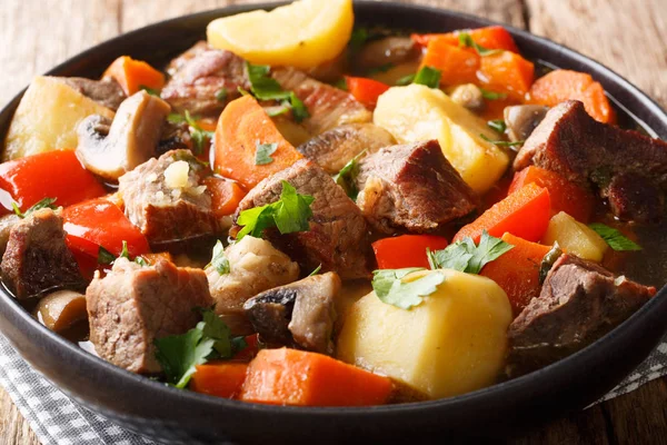 Porco cozido grosso saboroso com cogumelos, batatas, cenouras e pepp — Fotografia de Stock