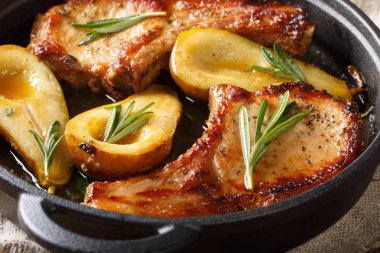 Bir tavada armut, biberiye ve bal ile pişmiş domuz pirzolası yakın-u