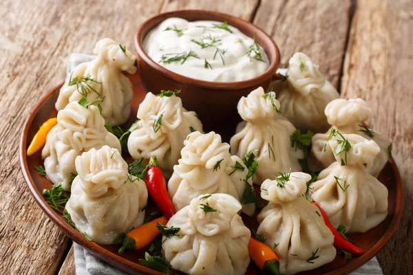 Juicy cooked khinkali dumplings with sour cream, pepper and herb